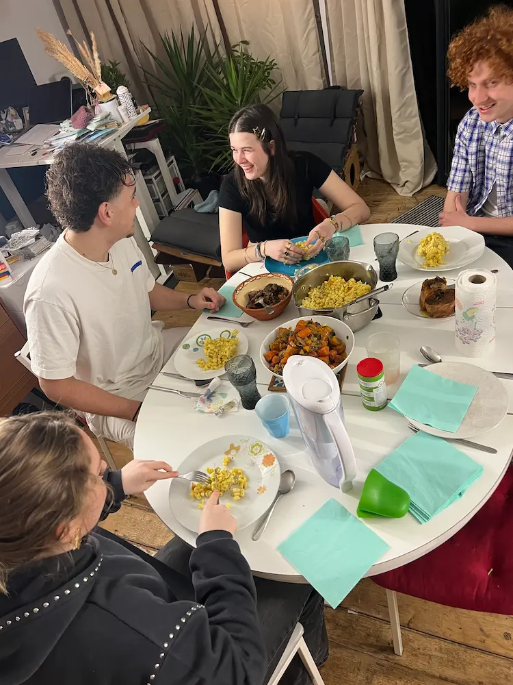 Adolescents discutant et riant autour d'un repas de famille sans smartphones, illustrant la médiation sociale par le débat.